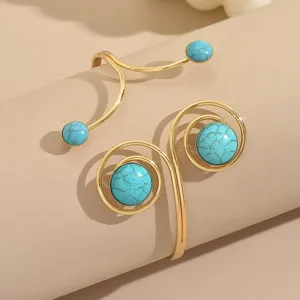 Dettaglio in primo piano del bracciale geometrico dorato con vivaci pietre turchesi.