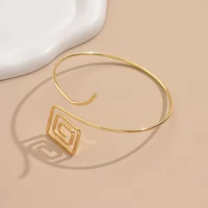 Primo piano dettagliato di un bracciale da braccio aperto geometrico dorato alla moda, chic.
