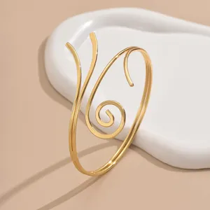 Goldener offener Armreif mit mehrschichtigem geometrischem Spiraldesign, Detailaufnahme.