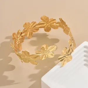 Dettaglio bracciale da braccio in metallo dorato, elegante polsino floreale in primo piano.