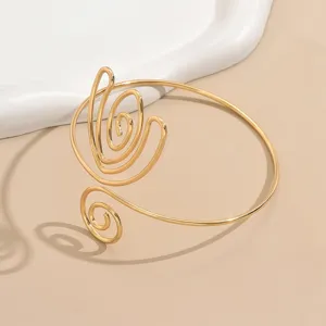 Bracciale da braccio aperto in filo dorato con design geometrico a spirale floreale. Vista dettaglio.