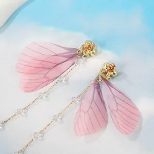 Primo piano dettagliato di orecchini ad ali di fata rosa con catene di cristallo.