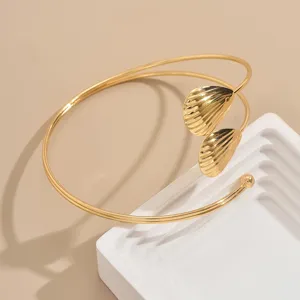 Primo piano dettagliato di bracciale da braccio dorato con conchiglia e design multistrato.