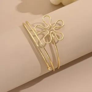 Bracciale da braccio geometrico dorato minimalista con fiore cavo, dettaglio aperto.