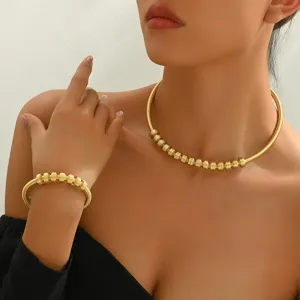 Detailed close-up of gold-plated ribbed metal choker necklace and matching bracelet jewelry set.