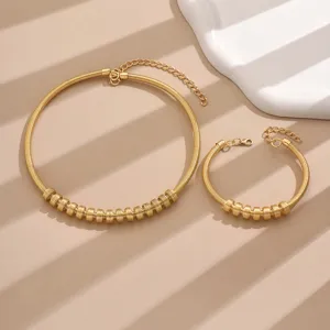 Detail shot of trendy gold tone coil necklace and bracelet set with sliding bead accents.