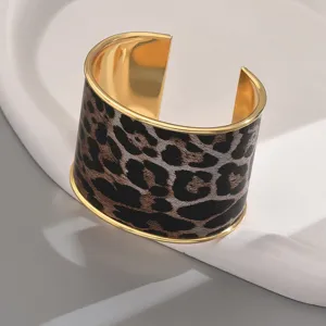 Wide leopard print open cuff bracelet for women, stylish gold-rimmed geometric metal wrist jewelry.