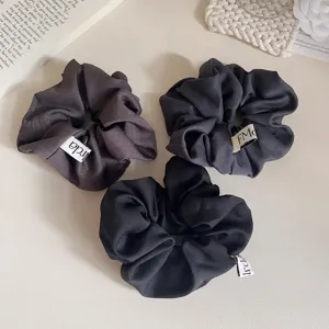 Detail van eenvoudige donkergrijze stoffen haarelastiekjes, elegante paardenstaart haarbanden.