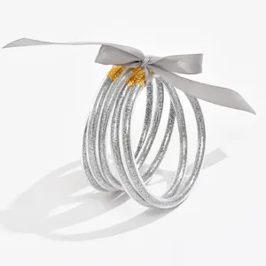 Detailopname van transparante glitterarmbanden met een elegante grijze strik eromheen.