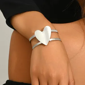 Close up detail view of silver metal open cuff bracelet featuring a distinct geometric heart.