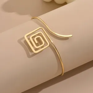 Dettaglio in primo piano del moderno bracciale rigido geometrico quadrato aperto oro.