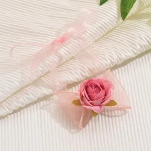 Primo piano dettagliato di un braccialetto in nastro di organza rosa con rosa in tessuto plissettato.