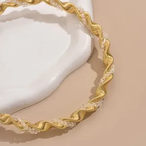 Close-up view of geometric spiral twisted metal choker necklace with clear crystals.