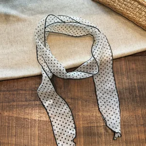 Detalle de bufanda larga y estrecha de lunares chic, elegante cinta para cuello y pelo.