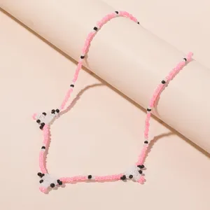 Close-up detail of a cute Korean bohemian seed bead cow pattern necklace in pink and black.