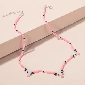 Close-up of beaded animal necklace detail showing pink seed beads and metal clasp.