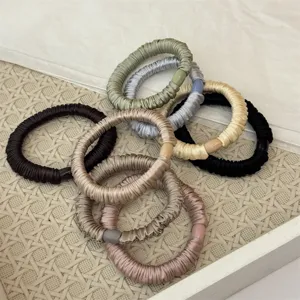 Nahaufnahme Detail von bunten Satin Plissee Haar-Scrunches auf gewebtem Tablett Display.