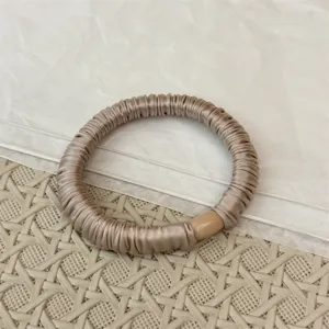 Detailansicht eines koreanischen Satin Falten Haargummis in elegantem Champagner.