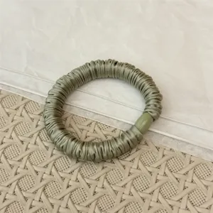 Grüne Satin Falten Haargummi Detailaufnahme zeigt feine Textur und elastisches Material.