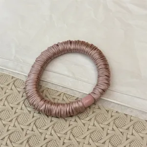Nahaufnahme eines eleganten plissierten Satin Haargummis mit feiner glänzender Stoffstruktur.