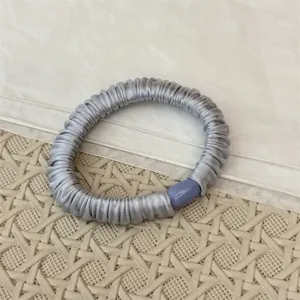 Graues Satin Plissee Haargummi mit eleganter hellblauer Perle, elastisches Haarband Detail.