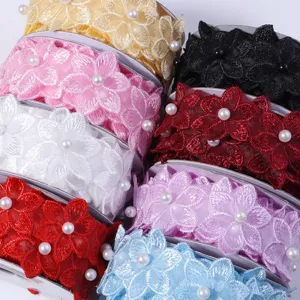 Close-up detail of colorful embroidered lace trim with pearl beads for DIY craft and sewing.