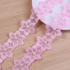 Close-up of pink embroidered lace trim featuring beaded pearl six-petal flowers for DIY crafts.