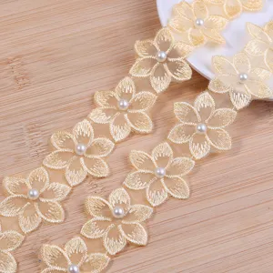 Detailed close-up of embroidered six-petal flower lace trim with pearl beading for DIY crafts.