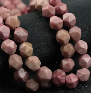 Primo piano di perline in pietra naturale rosa sfaccettate per la creazione di gioielli.