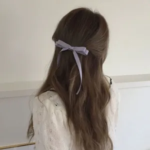 Nahaufnahme Detailaufnahme einer hellvioletten Schleifen Haarspange im langen braunen Haar.
