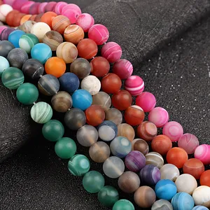 Primo piano di perline rotonde in agata satinata colorata, accessori per gioielli fai-da-te.