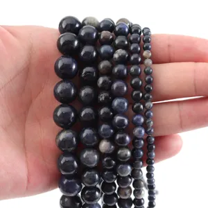 Hilar de cuentas de piedras preciosas azules en la mano para accesorios de joyería.