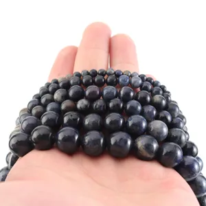 Cuentas de piedras redondas azul oscuro sostenidas en mano, ideales para hacer joyas de pulseras DIY.