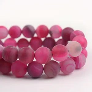 Primo piano perline di agata satinata rosa, accessori fai da te semilavorati a righe.