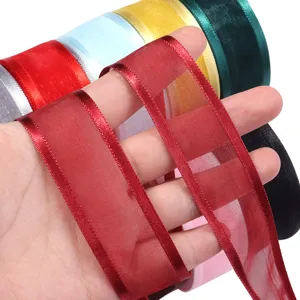 Nahaufnahme von breitem transparentem Organzaband in Hand, feines Detail für Geschenke.