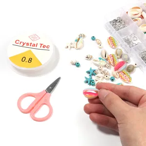 Detail view of DIY jewelry making kit components, colorful shells, elastic cord and scissors.