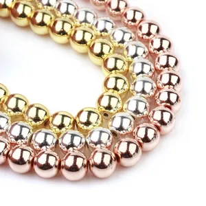 Primer plano detallado de cuentas redondas metálicas en oro, plata y oro rosa para joyería.