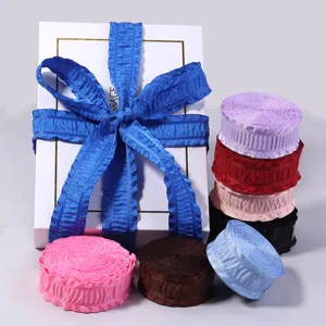 Nahaufnahme von bunte plissierte Rüschenbändern und Geschenkbox mit blauer Schleife.