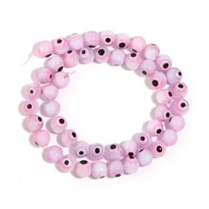 Detailed close-up of pink glass evil eye beads strand, perfect for DIY jewelry making and crafts.