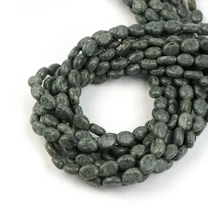Nahaufnahme Detail von gruenen flachen ovalen Naturstein Perlen Strang fuer DIY Schmuck.