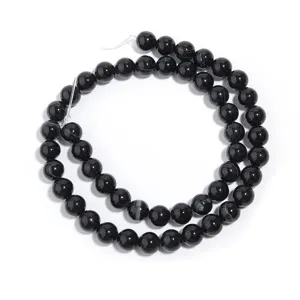 Primo piano di perline di agata nera striata, pietre naturali rotonde per creazione di gioielli.