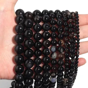 Close up view of polished black agate round beads, smooth gemstone strand for jewelry DIY.
