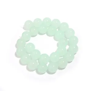 Nahaufnahme von hellgrünen Chalcedon Perlen, polierte runde Edelsteine für DIY Schmuck.