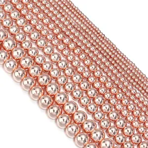 Detail view of rose gold metallic smooth round loose beads, showcasing multiple graduating sizes.
