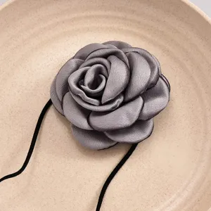 Gros plan détaillé du pendentif en tissu gris élégant, mettant en valeur les pétales délicats.