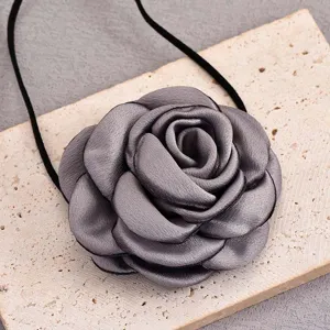 Gros plan détaillé d'un collier de fleurs en tissu gris, montrant une texture délicate.