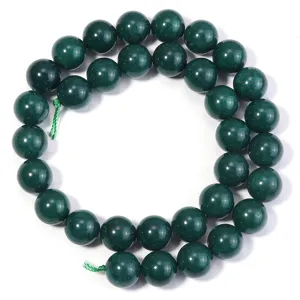 Detailed shot of dark green natural stone loose beads, smooth surface, jewelry making accessory.