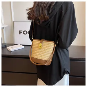 Dettaglio di una borsa a secchiello vintage in paglia intrecciata con finiture in pelle marrone.