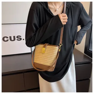 Dettaglio di una borsa a secchiello vintage in paglia con finiture in pelle marrone.