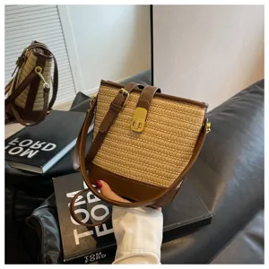 Dettaglio di una borsa a secchiello in paglia retrò con trama intrecciata e pelle marrone